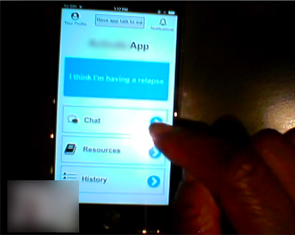 a screenshot of the usability test with the participant tapping a button on the mobile app prototype. There is a thumbnail of the participant's face blurred out in the bottom left